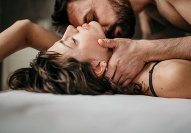 Un couple dans un lit, l'homme la main sur le cou de la femme