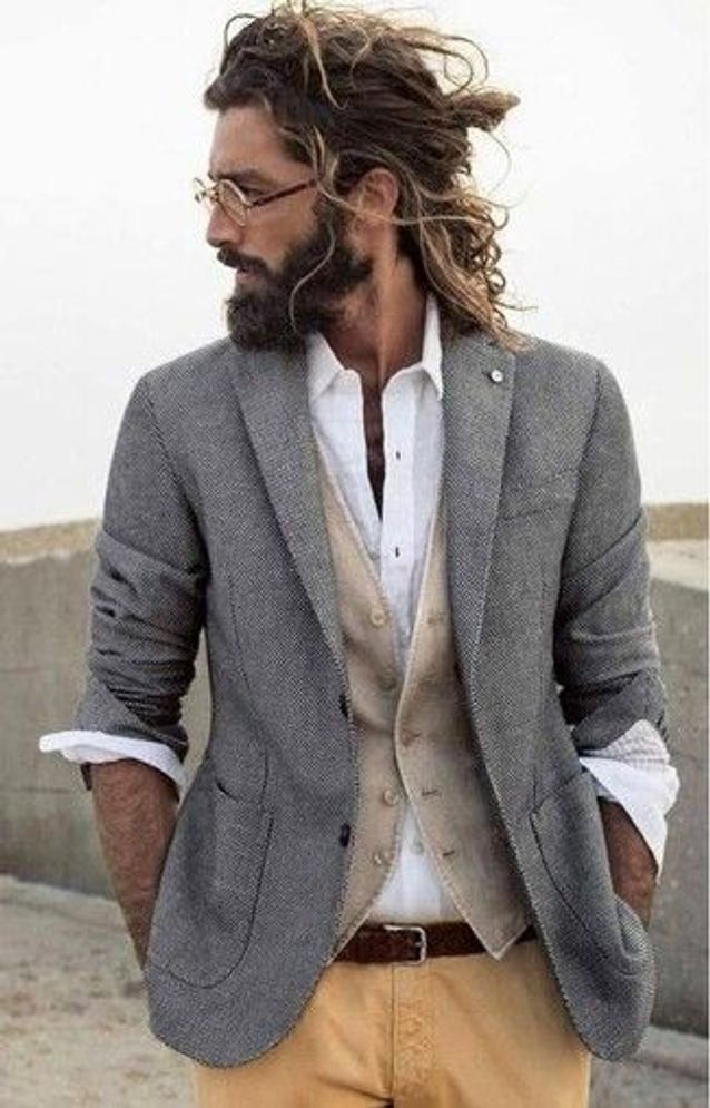 Homme sérieux avec des cheveux longs et une barbe sur une plage de