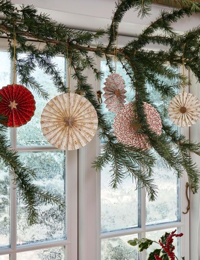 Noël : on décore la maison avec des guirlandes et des suspensions en papier devant les fenêtres