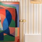 Dans le couloir, un papier peint rétro et un tableau multicolore de Caroline Denervaud jouent les contrastes