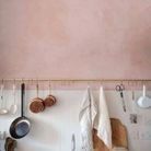Un mur de cuisine rose accessoirisé d'une barre de crédence dorée