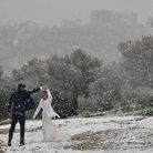 De jeunes mariés dansent dans la neige avec pour fond, l'Acropole 